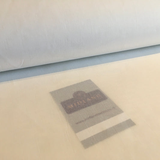 Roll of fabric with a label on a beige surface