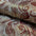 Close-up of patterned fabric with red and gold designs on a beige background